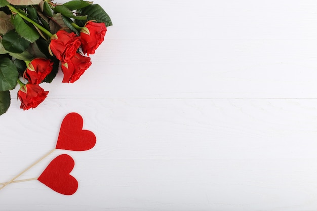 Czerwone róże i serca na białym drewnianym stole