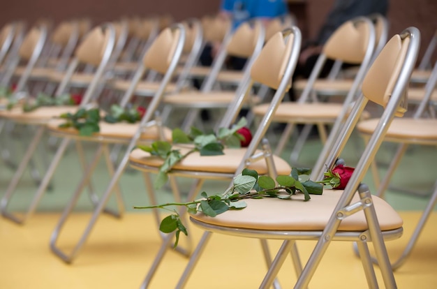 Czerwone róże leżą na pustych krzesłach Rząd krzeseł z kwiatami