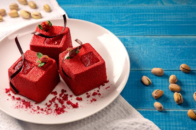Czerwone torty w kształcie kostek z pistacjami biszkoptowymi sufletem czekoladowym konfiturą malinową i kruszonką orzechową