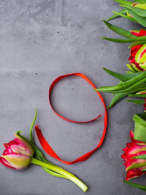 Czerwone tulipany z czerwoną wstążką na białym tle na betonowym tle Dzień zwycięstwa lub dzień obrońcy ojczyzny