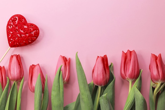 Czerwone tulipany z czerwonym sercem na różowym tle widok z góry miejsca kopiowania