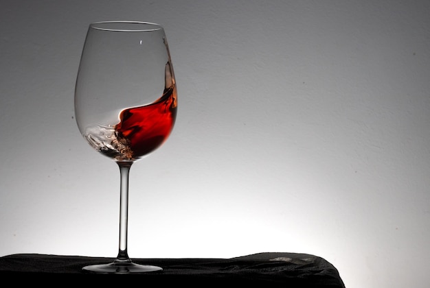 Czerwone wino rozpryskujące się w szklance na białym tle