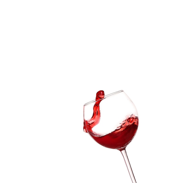 Czerwone wino rozpryskujące się ze szkła na białym tle