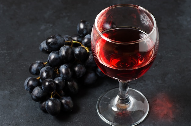 Czerwone wino w szklance, kiść winogron.