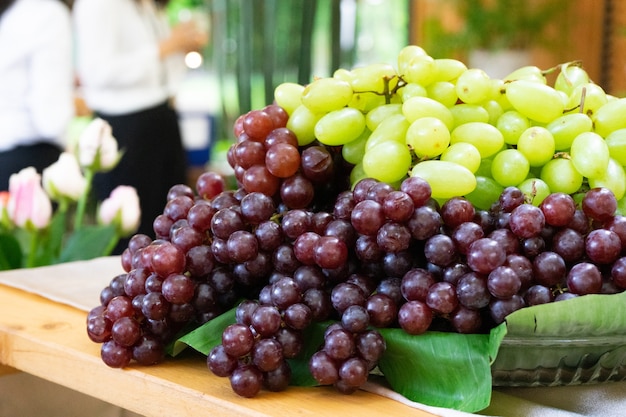 Czerwone winogrona na szklanej płycie schodkowej stoją samotnie na drewnianym stole w ogrodzie na świeżym powietrzu rozmycie bokeh.