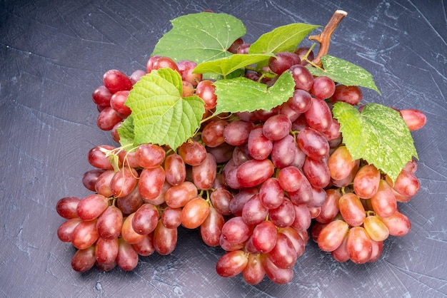 Czerwone winogrona z liśćmi na drewnianym tle Kiść świeżych czerwonych winogron z liśćmi