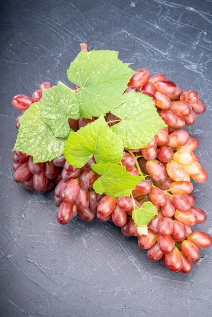 Czerwone winogrona z liśćmi na drewnianym tle Kiść świeżych czerwonych winogron z liśćmi