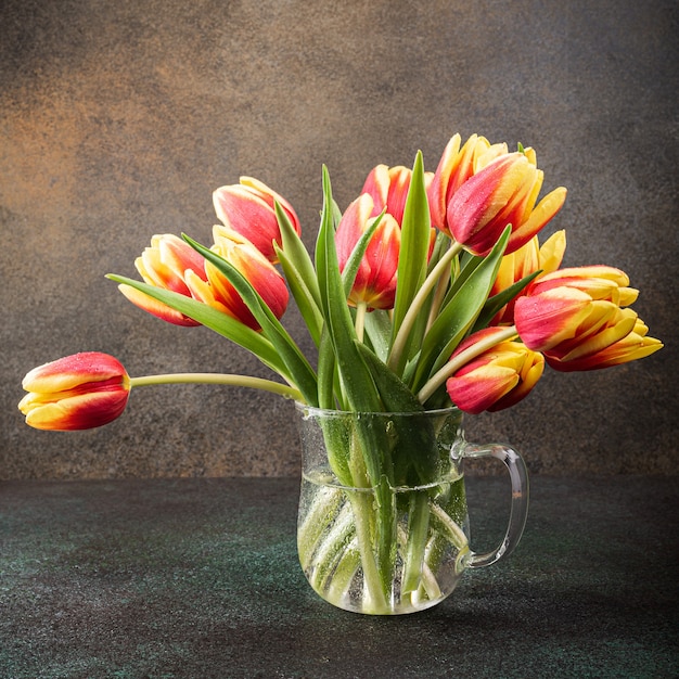 Czerwone żółte tulipany w szklanych wazonach. Prezent na dzień kobiety. Kartkę z życzeniami na dzień matki. Świętujemy Wielkanoc. Skopiuj miejsce