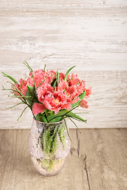Czerwoni i biali puszysti tulipany w wazie na drewnie