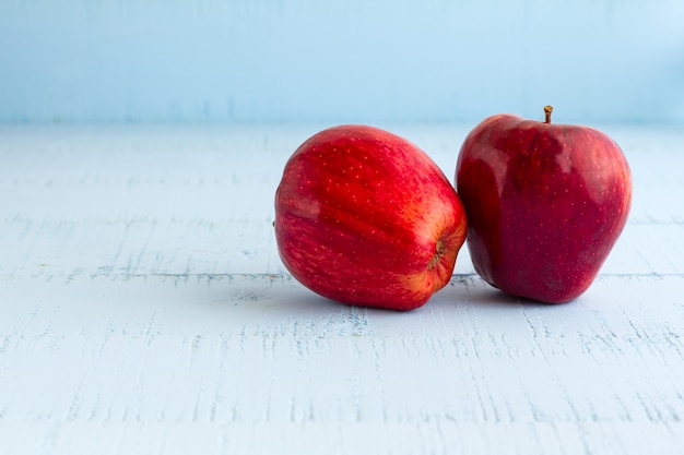 Czerwoni jabłka na drewnianym błękita stole.