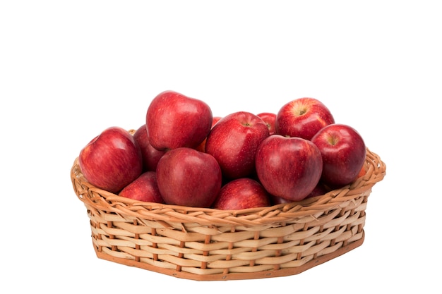 Czerwoni jabłka w łozinowym koszu na białym tle