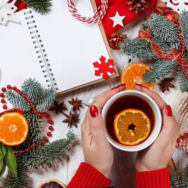 Czerwono-złota świąteczna kompozycja z notatnikiem i kubkiem do herbaty