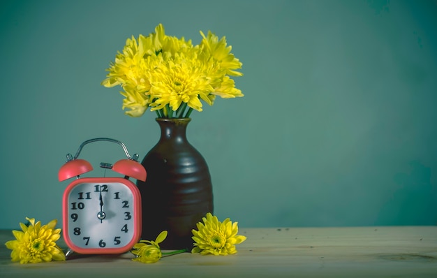 Zdjęcie czerwony alarm, żółta kwiat chryzantema na drewnianym przy południem.