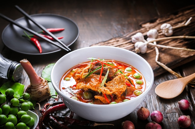 Czerwony curry z wieprzowiną i kokosowym mlekiem, wyśmienicie Tajlandzki jedzenie na drewnianym stole.