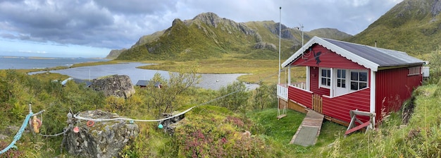 Czerwony dom na łące z widokiem na morze na szczycie góry w Norwegii archipelag westeralen wyspa Langoya