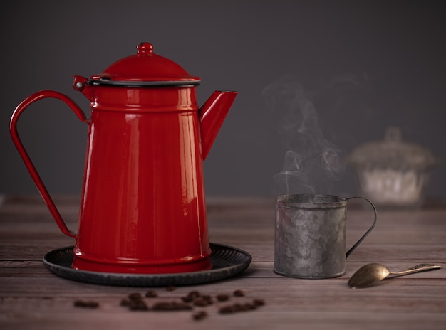 czerwony emaliowany ekspres do kawy z metalową filiżanką parującej kawy