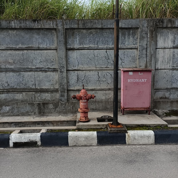 Zdjęcie czerwony hydrant przed szarą ścianą na ulicy