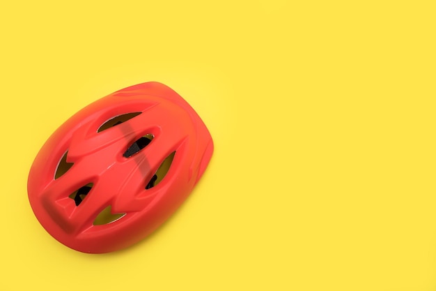 Czerwony kask rowerowy na żółtym tle z miejscem na kopię