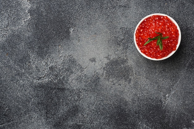 Czerwony kawior z łososia w talerzu na ciemnym betonie. Skopiuj miejsce Przysmak z przekąsek.