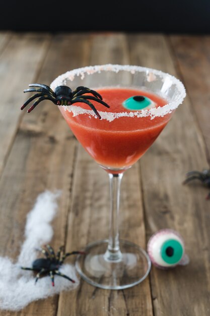 Czerwony kolorowy koktajl na dzień Halloween z pająkiem i oko na rustykalne drewniane tła. Skopiuj miejsce.