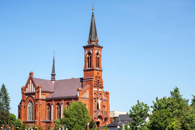 Czerwony kościół katolicki z cegły na niebieskim tle
