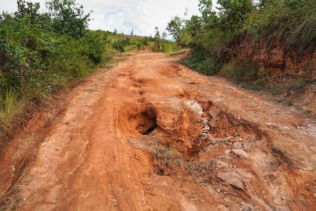 Czerwony kurz i błoto droga w złym stanie z dużymi dziurami i wybojami powstałymi po deszczu. Trasy do Parku Narodowego Andringitra są wyjątkowo złe w porze deszczowej w regionie w pobliżu Sendrisoa na Madagaskarze