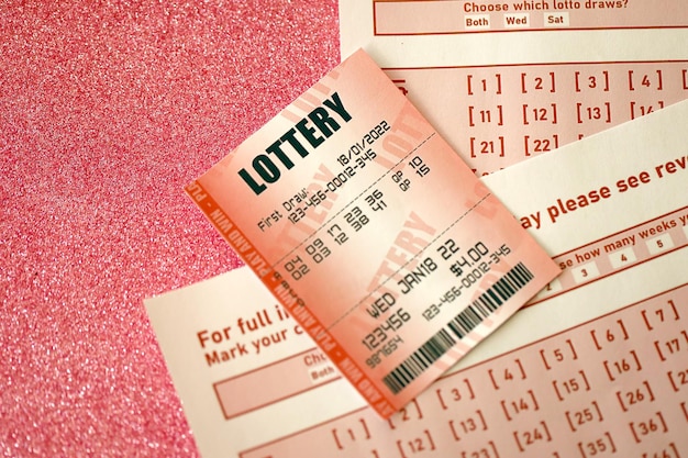 Czerwony los na loterię leży na różowych arkuszach hazardowych z numerami do oznaczenia do gry w loterię Koncepcja gry na loterii lub uzależnienie od hazardu Zbliżenie