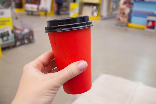 Czerwony papierowy kubek z kawą lub herbatą w rękach dziewczynki Makieta