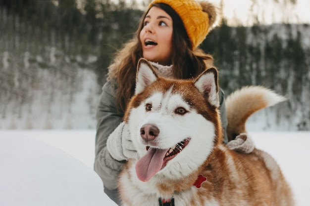 Czerwony psi husky z jego kochanki brunetki dziewczyną w lesie outdoors w zimnym sezonie