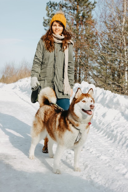 Czerwony psi husky z jego kochanki brunetki dziewczyną w lesie outdoors w zimnym sezonie