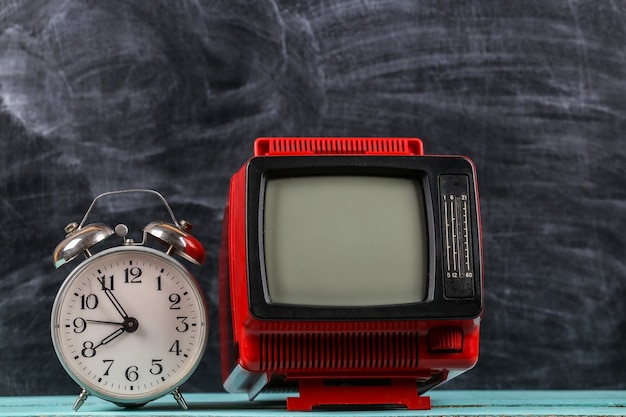 Zdjęcie czerwony retro old school przenośny mini telewizor z budzikiem na tle tablicy