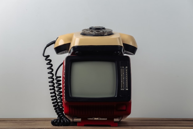 Zdjęcie czerwony retro stary przenośny mini telewizor z obrotowym telefonem na białym tle.