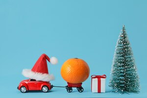 Czerwony samochód dostarczający mandarynki, pudełko na prezenty na niebieskim tle dostawa produktu boże narodzenie