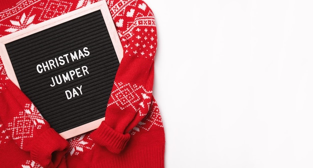 Czerwony świąteczny sweter i tablica z napisami Christmas Jumper Day