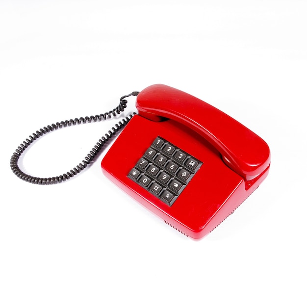 Czerwony telefon vintage z przyciskami na białej izolowanej powierzchni