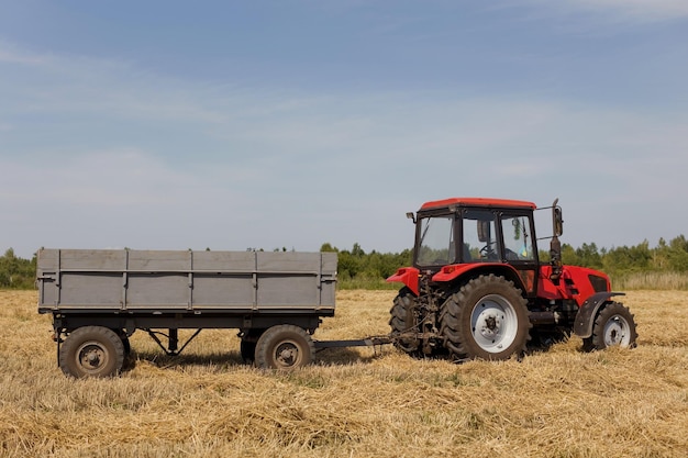 Czerwony traktor z przyczepą w polu