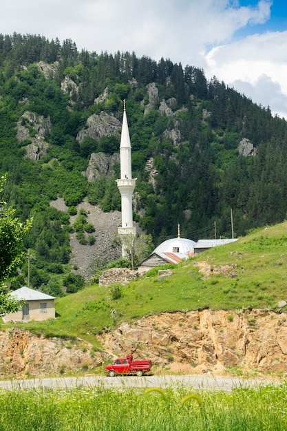 Czerwony van na drodze, meczet i minaret w tle. Giresun - Turcja