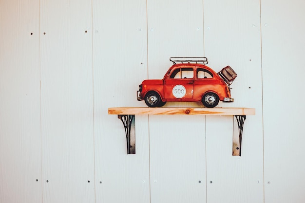 Czerwony zabawkowy samochód na półce przy białej ścianie