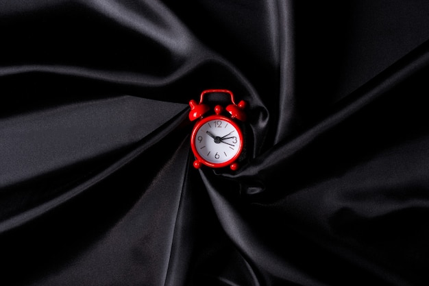 Czerwony zegar na czarnym materiale. Czas na zakupy.