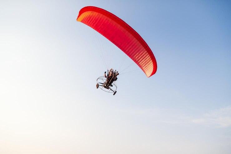 Zdjęcie czerwony zmotoryzowany paralotnia na niebieskim niebie leci z dwoma pasażerami w ciepły letni dzień sporty latające