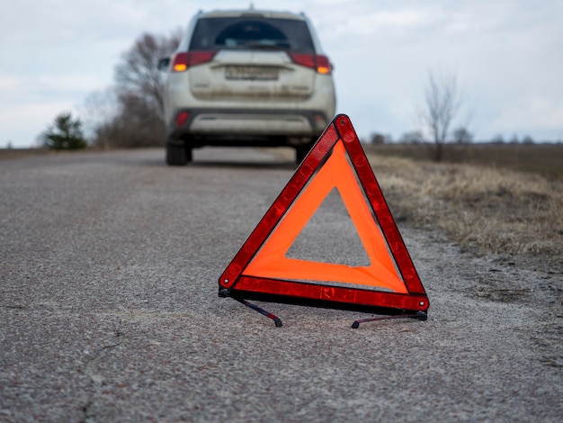 Czerwony znak stopu awaryjnego. W tle samochód się zatrzymał i migają światła awaryjne. Koncepcja wypadków, awarii, usług serwisowych