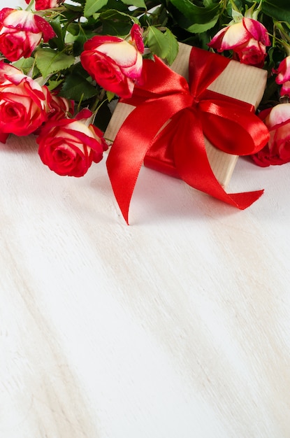 Czerwonych róż bukiet i teraźniejszość na drewnianym stole.