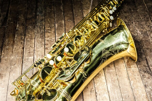 Zdjęcie część rurki z kieszeniami i dzwonkami żółtego saksofonu na starej drewnianej powierzchni