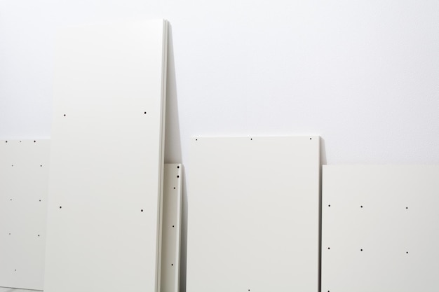 Części meblowe z płyty wiórowej pozostające przy ścianie gotowe do montażu szafy