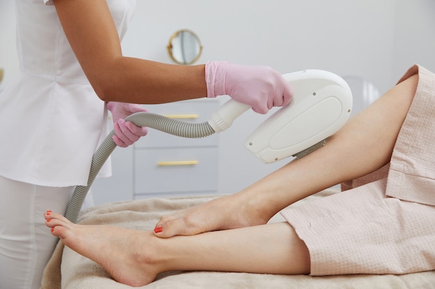 Częściowy widok kobiety otrzymującej depilację laserową na nodze w salonie