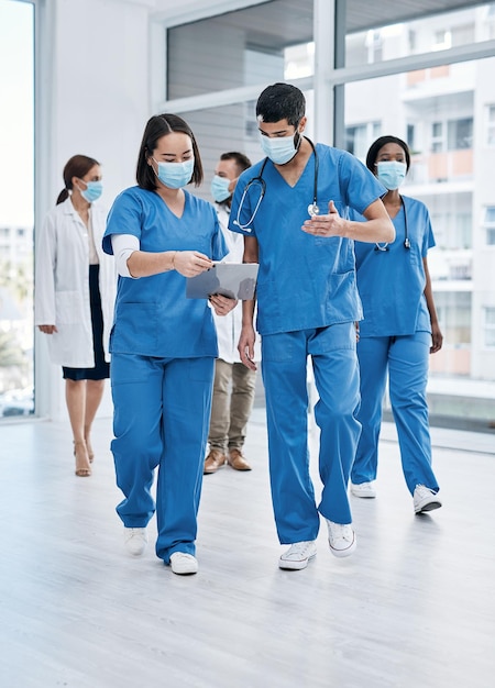 Często się komunikują i dzielą się zasobami w razie potrzeby Zdjęcie przedstawiające dwóch lekarzy przeglądających notatki podczas spaceru w ruchliwym szpitalu