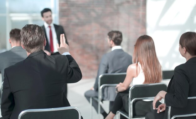 Członek personelu podnosi rękę na konferencji, aby odpowiedzieć na pytanie