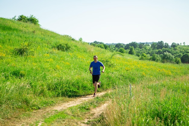 Człowiek biegacz jogging w wiejskiej scenie latem. Ciężki trening biegowy