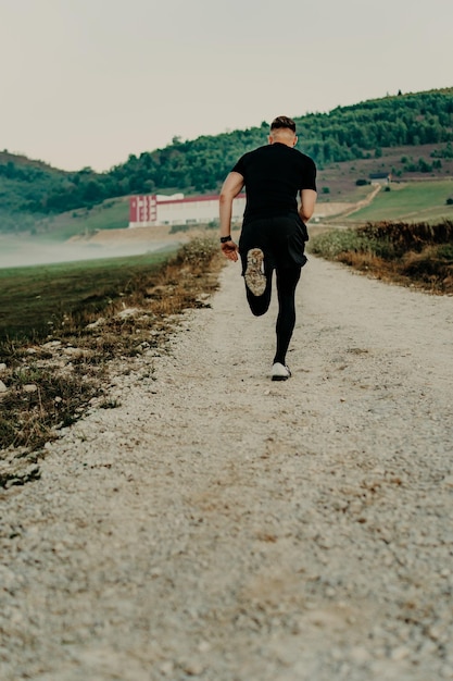 Człowiek biegający / sprintujący po drodze w górach. Sprawny męski biegacz fitness podczas treningu na świeżym powietrzu. Młody kaukaski mężczyzna.