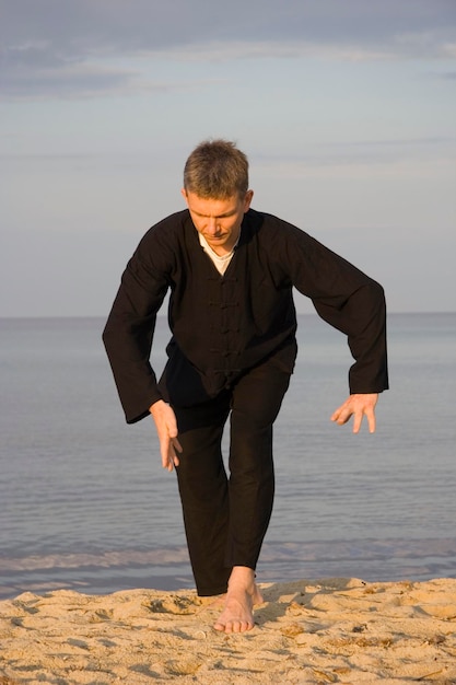 Zdjęcie człowiek ćwiczący tai chi na piasku na plaży